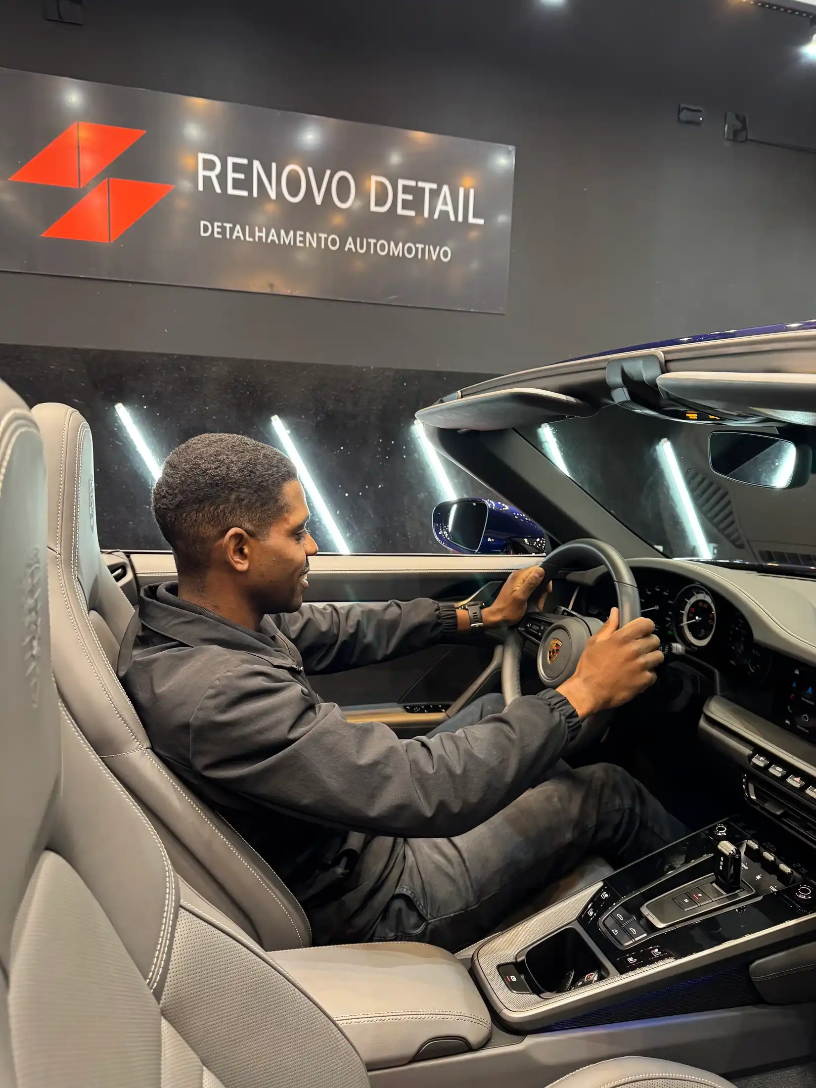 Profissional ao volante de Porsche com bancos de couro claro na Renovo